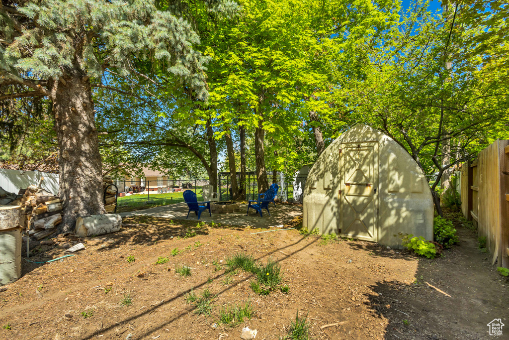 View of yard featuring a storage shed, an outbuilding, a fenced backyard, and a fire pit