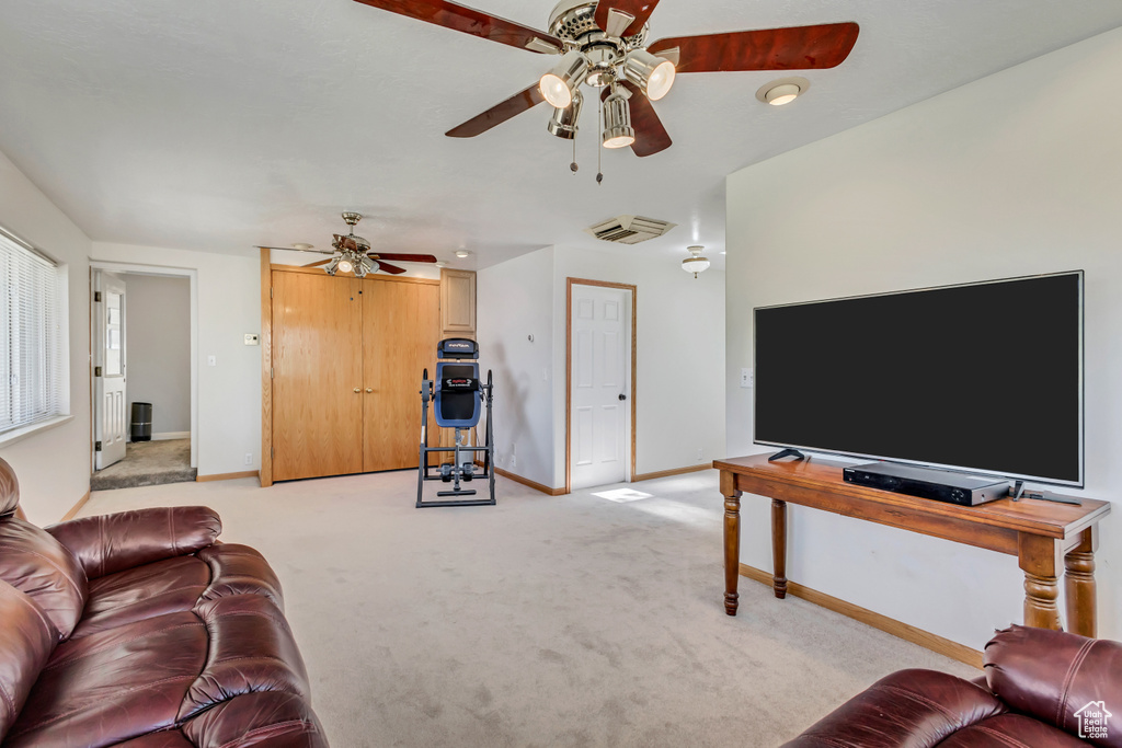 Living room featuring a ceiling fan, baseboards, and light carpet