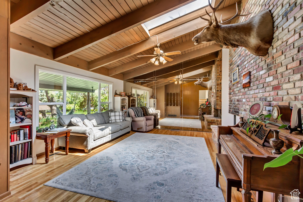 Living area featuring wood ceiling, ceiling fan, brick wall, and wood finished floors
