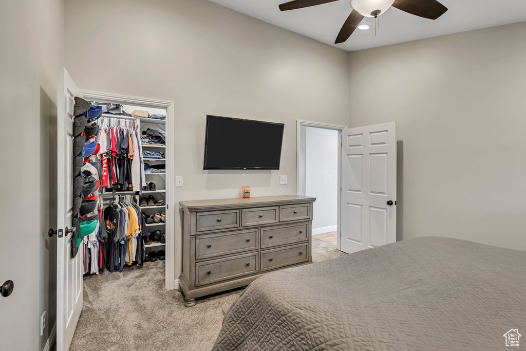 Bedroom featuring a closet, a towering ceiling, light carpet, a spacious closet, and a ceiling fan