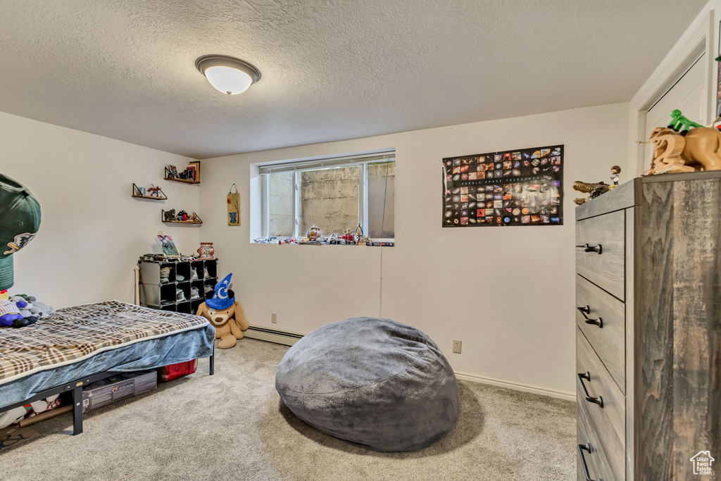 Carpeted bedroom with a textured ceiling and a baseboard radiator
