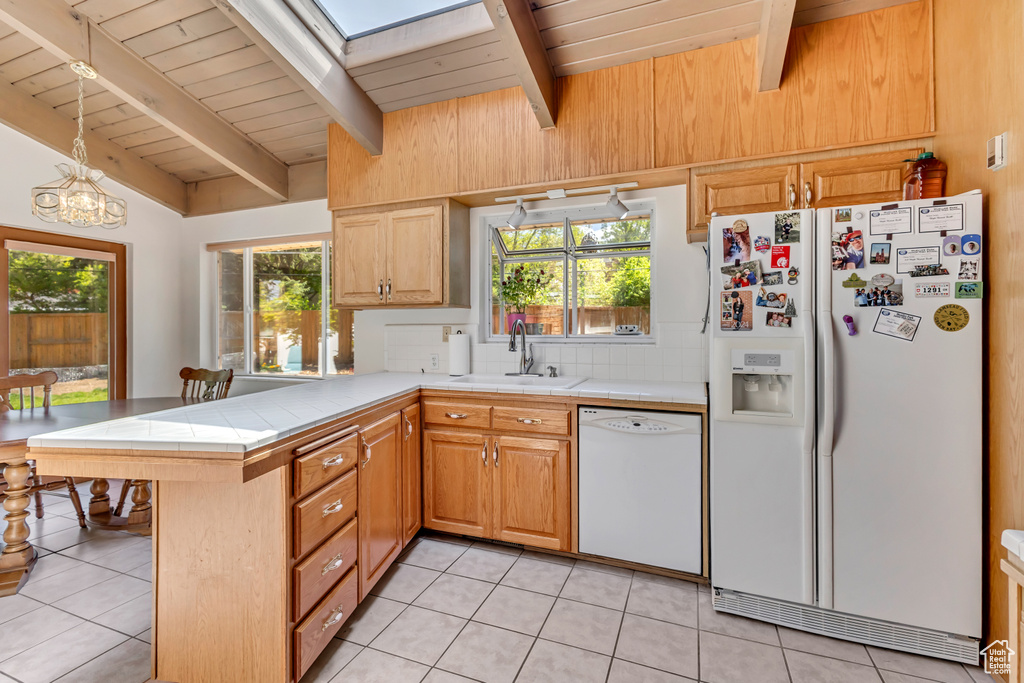 Kitchen with wood ceiling, tile countertops, a sink, a peninsula, and white appliances