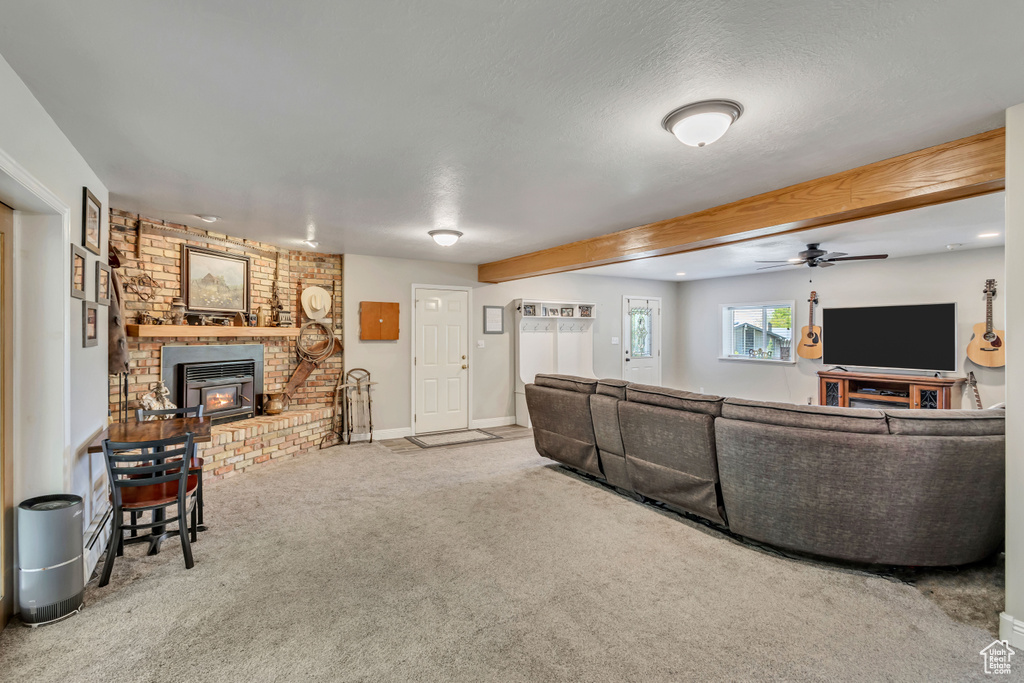 Carpeted living area with a ceiling fan, baseboards, and beam ceiling