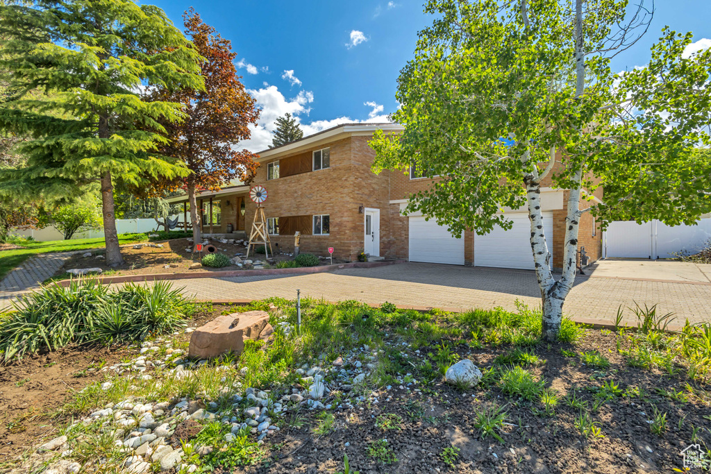 View of front of home featuring brick siding, decorative driveway, and fence