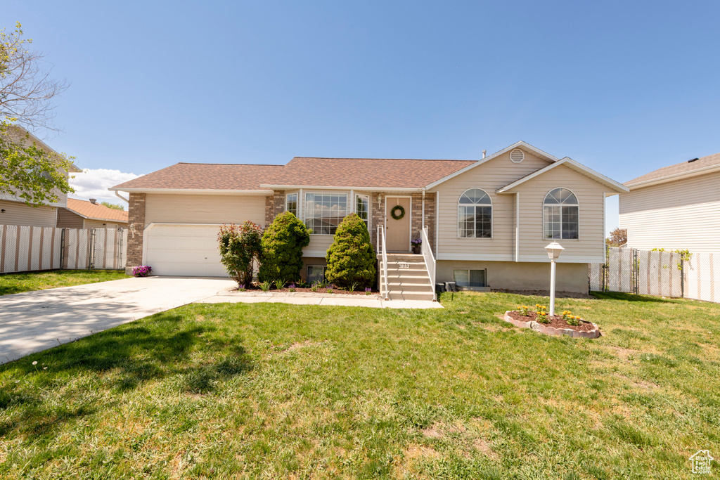 Ranch-style house with fence, driveway, a front yard, and a garage