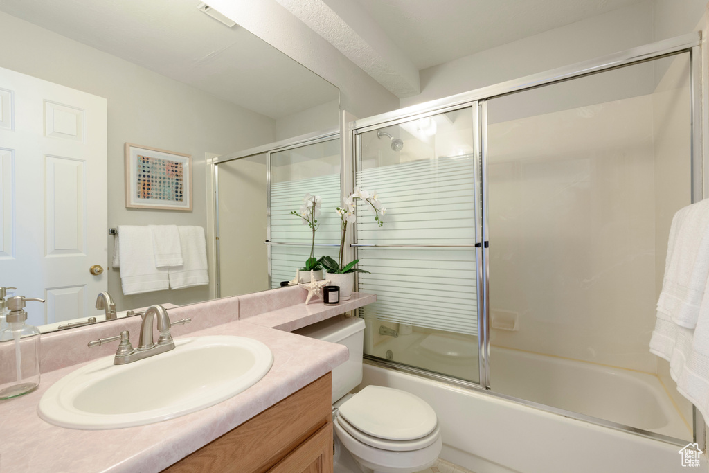 Full bathroom featuring vanity, enclosed tub / shower combo, and toilet