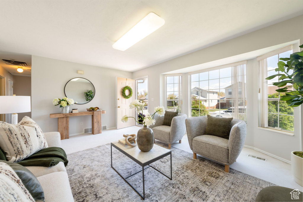 Living room with visible vents, baseboards, carpet floors, and a healthy amount of sunlight