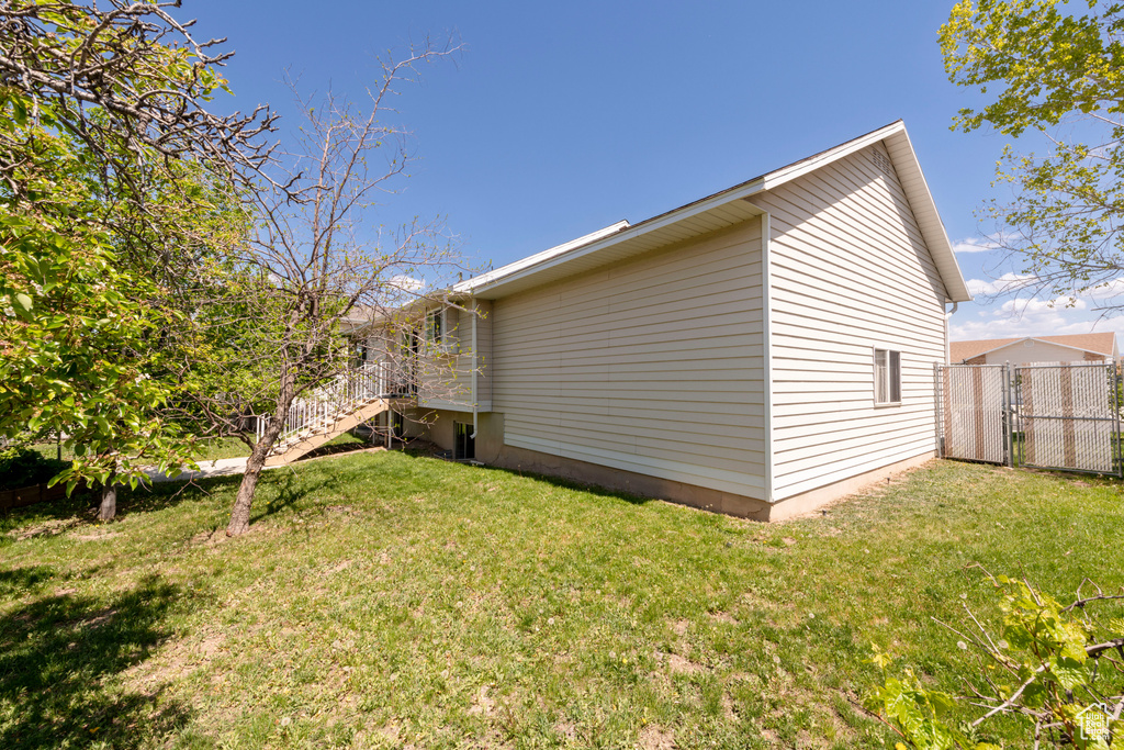 View of side of property with fence, stairs, and a yard