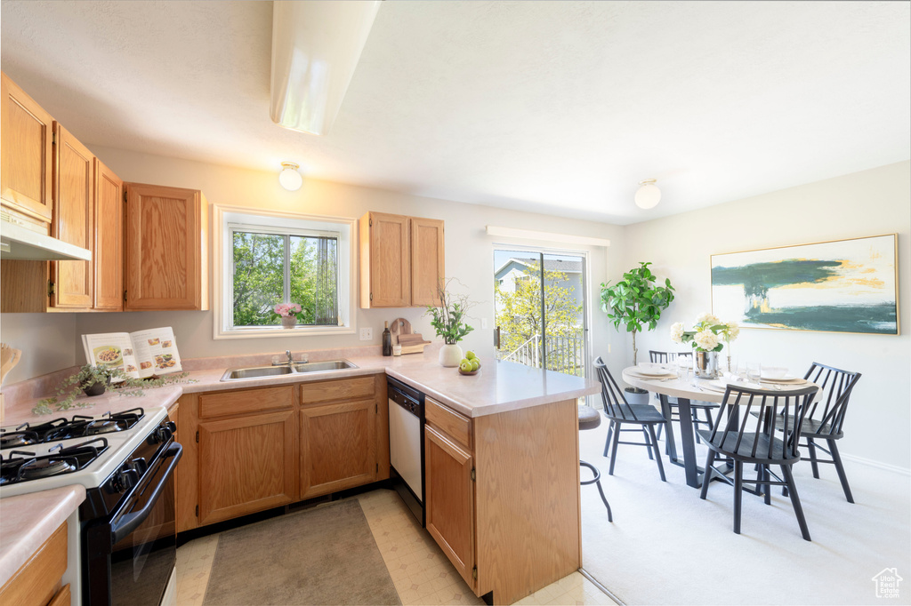 Kitchen featuring light countertops, a peninsula, a sink, and gas range