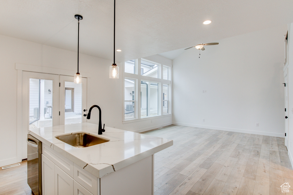 Kitchen featuring a sink, light wood finished floors, a ceiling fan, decorative light fixtures, and stainless steel dishwasher