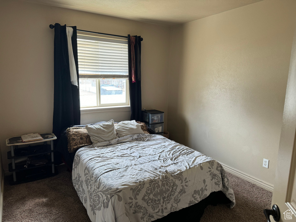 Bedroom with baseboards and dark colored carpet