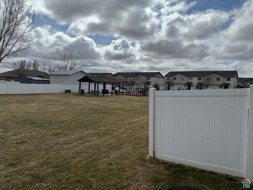 View of yard featuring a gazebo, fence, and a residential view