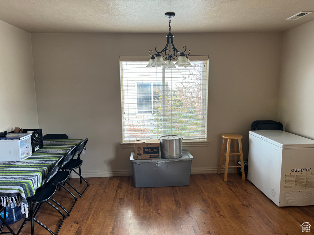 Dining room featuring baseboards, a chandelier, wood finished floors, and visible vents