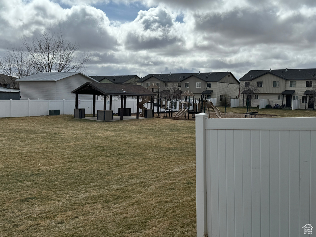 View of yard with a residential view, fence, a gazebo, and playground community