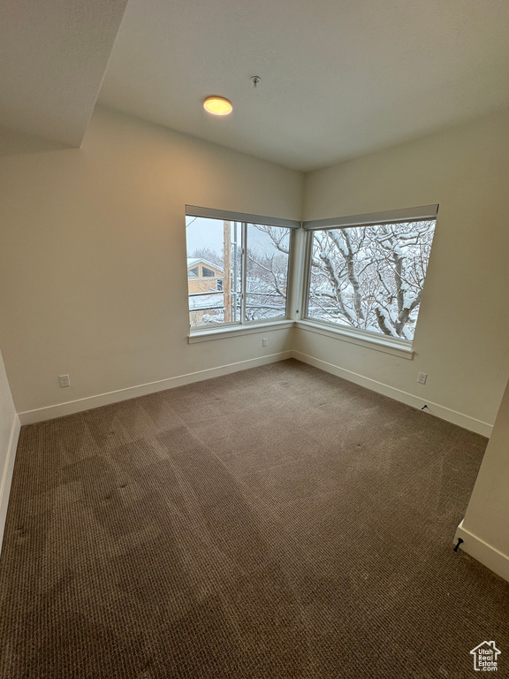 Unfurnished room with baseboards and dark colored carpet