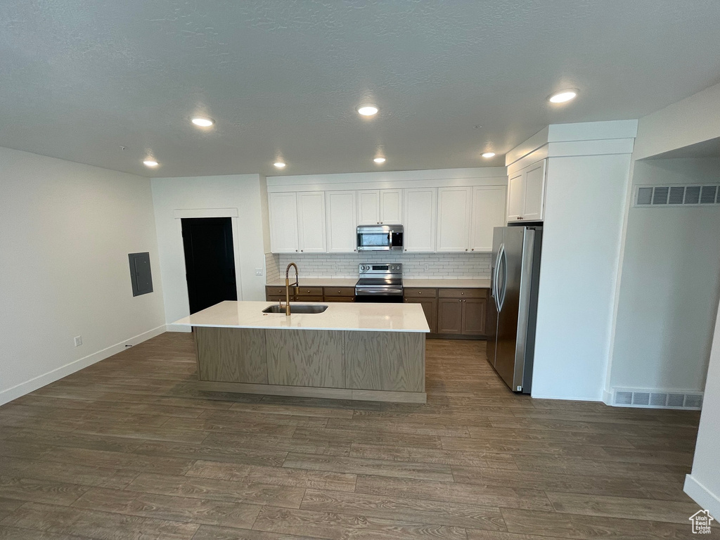 Kitchen with dark wood-style flooring, a sink, stainless steel appliances, decorative backsplash, and visible vents