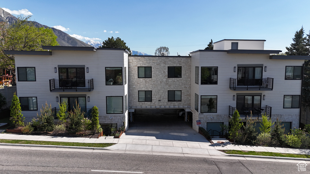 View of property with a mountain view and concrete driveway