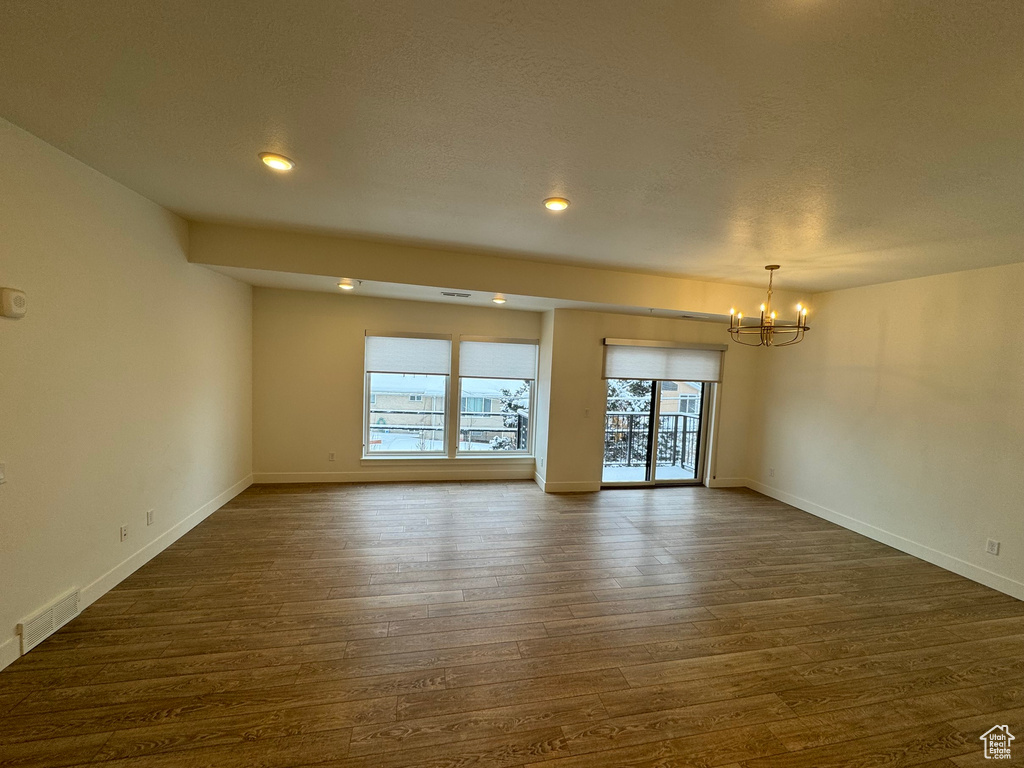 Unfurnished room featuring visible vents, baseboards, dark wood-style floors, a notable chandelier, and recessed lighting