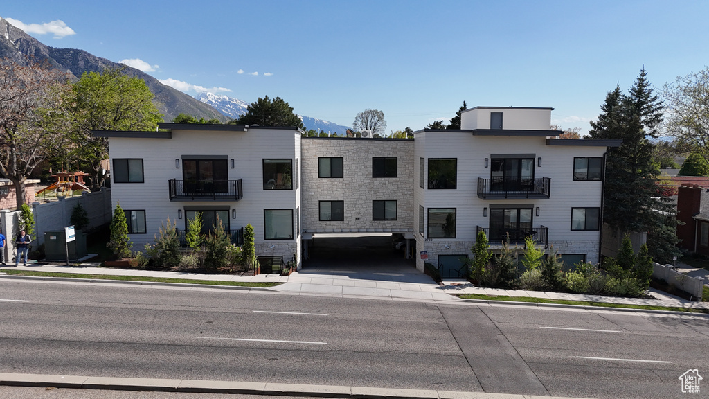 View of front of home with a mountain view, stone siding, and a balcony