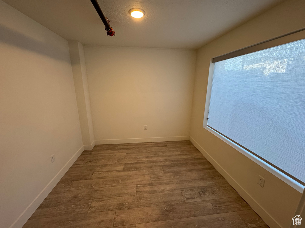 Spare room with baseboards, track lighting, and wood finished floors