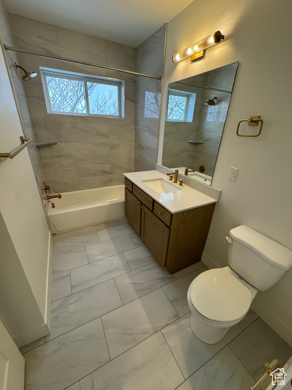 Bathroom featuring a healthy amount of sunlight, toilet, shower / tub combination, and marble finish floor