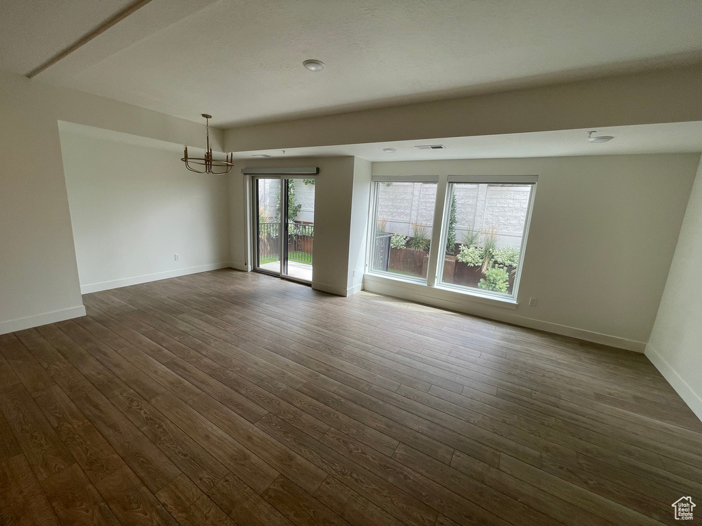 Unfurnished room featuring baseboards, a chandelier, dark wood-style floors, and visible vents