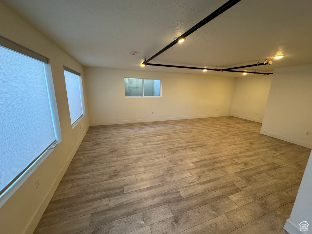 Unfurnished room with baseboards, a textured ceiling, and wood finished floors