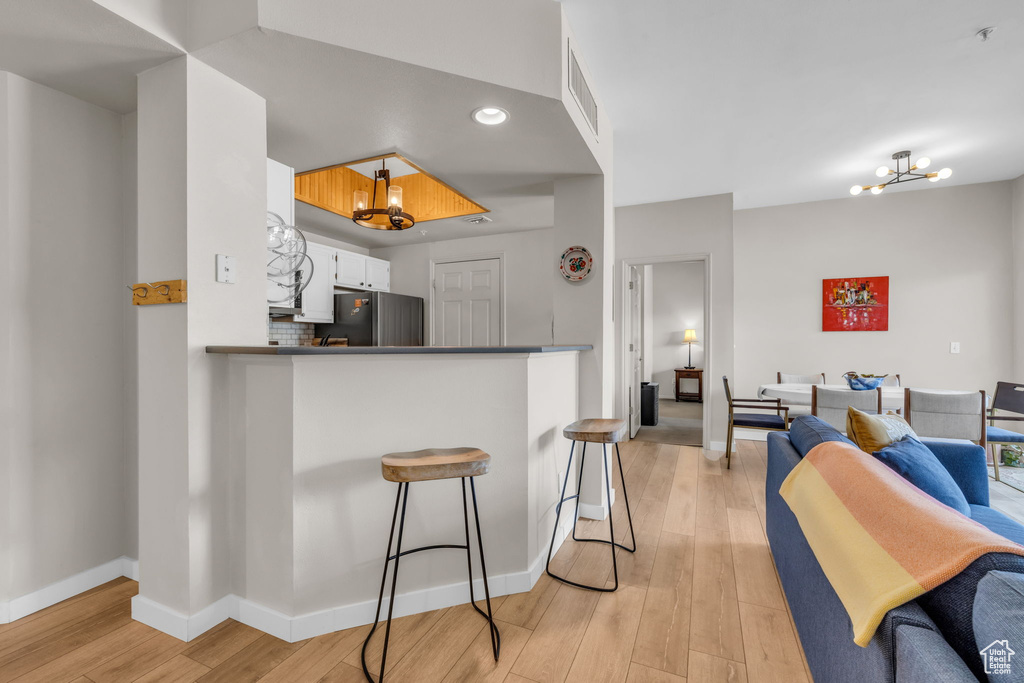 Kitchen with visible vents, freestanding refrigerator, open floor plan, light wood finished floors, and a notable chandelier