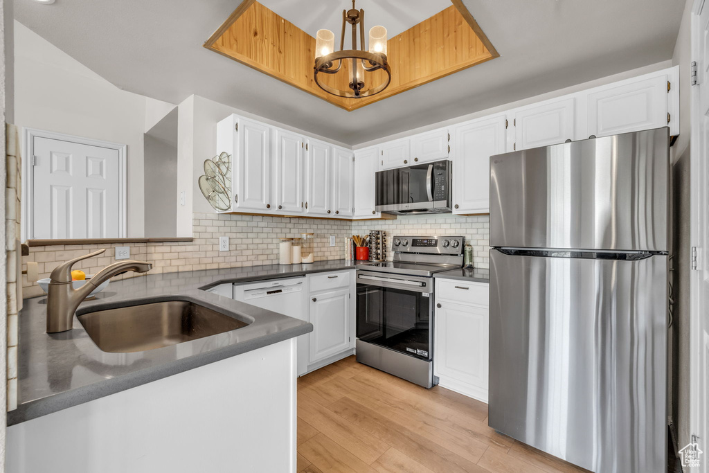 Kitchen featuring white cabinets, dark countertops, appliances with stainless steel finishes, and a sink