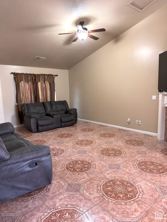 Living room with visible vents, a textured ceiling, ceiling fan, and vaulted ceiling