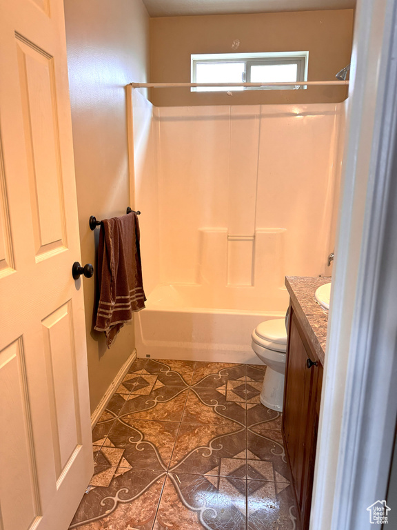 Bathroom with tile patterned flooring, vanity, baseboards, toilet, and  shower combination