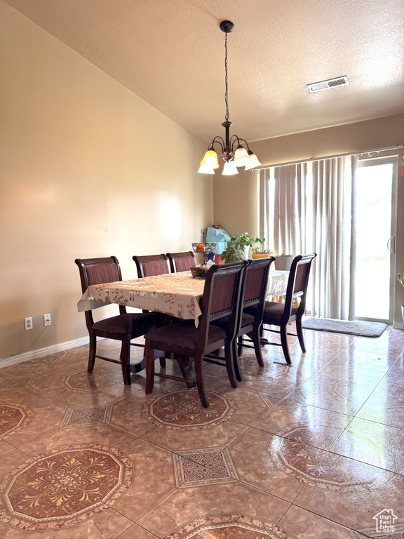 Dining area with an inviting chandelier, a textured ceiling, baseboards, and visible vents