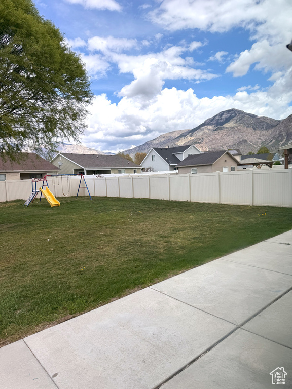 View of yard with a playground, a mountain view, and a fenced backyard