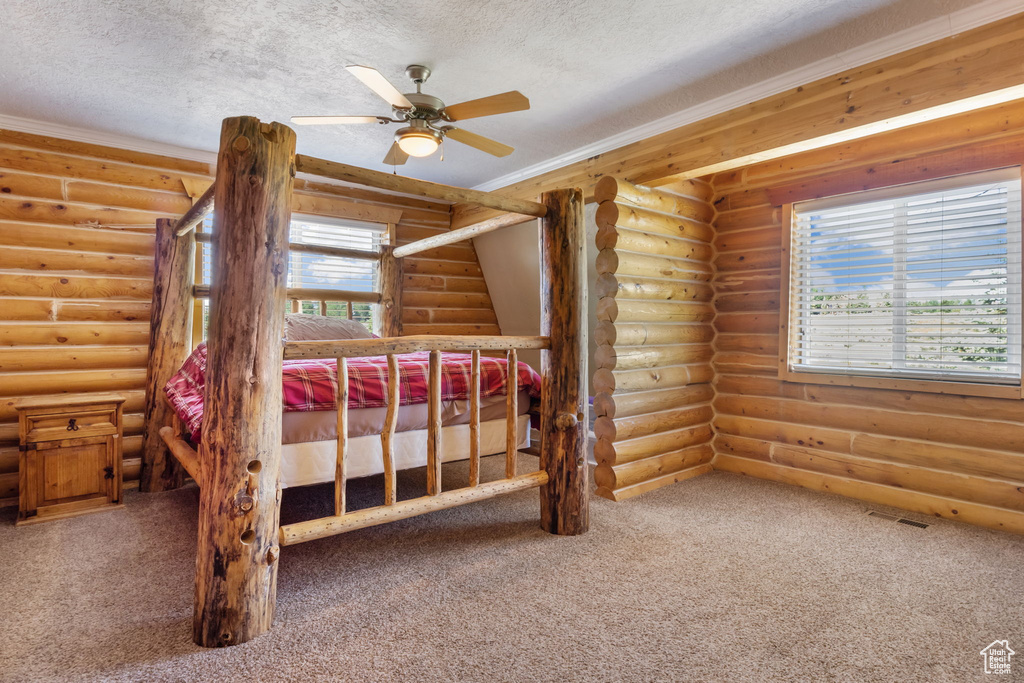 Unfurnished bedroom featuring rustic walls, carpet flooring, a textured ceiling, and visible vents