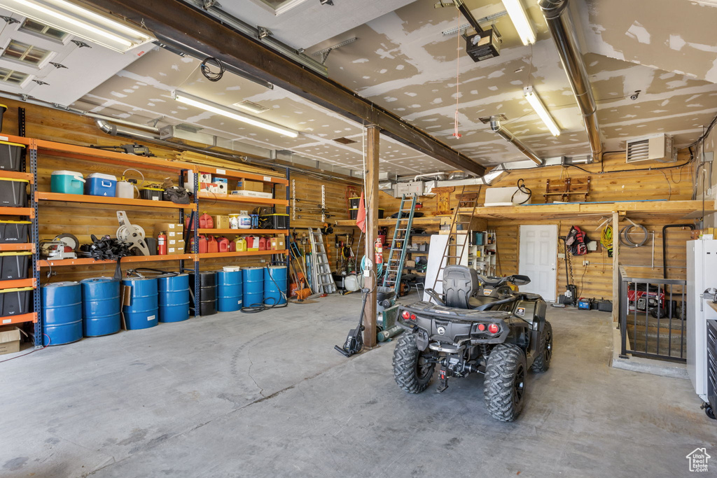 Garage with a workshop area, a garage door opener, and visible vents