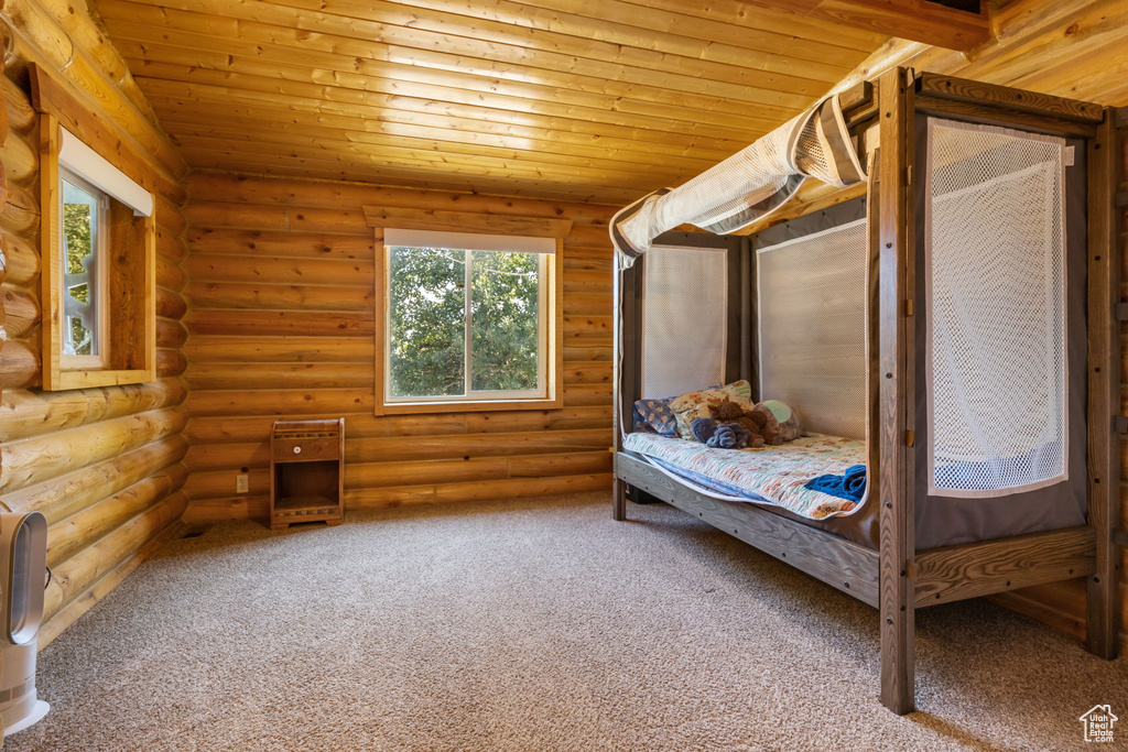Bedroom featuring rustic walls, multiple windows, and wooden ceiling