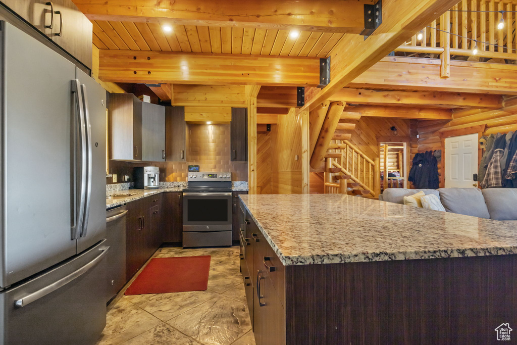 Kitchen with beam ceiling, dark brown cabinets, open floor plan, wood ceiling, and appliances with stainless steel finishes
