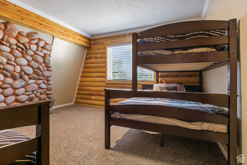 Carpeted bedroom featuring baseboards, ornamental molding, and rustic walls