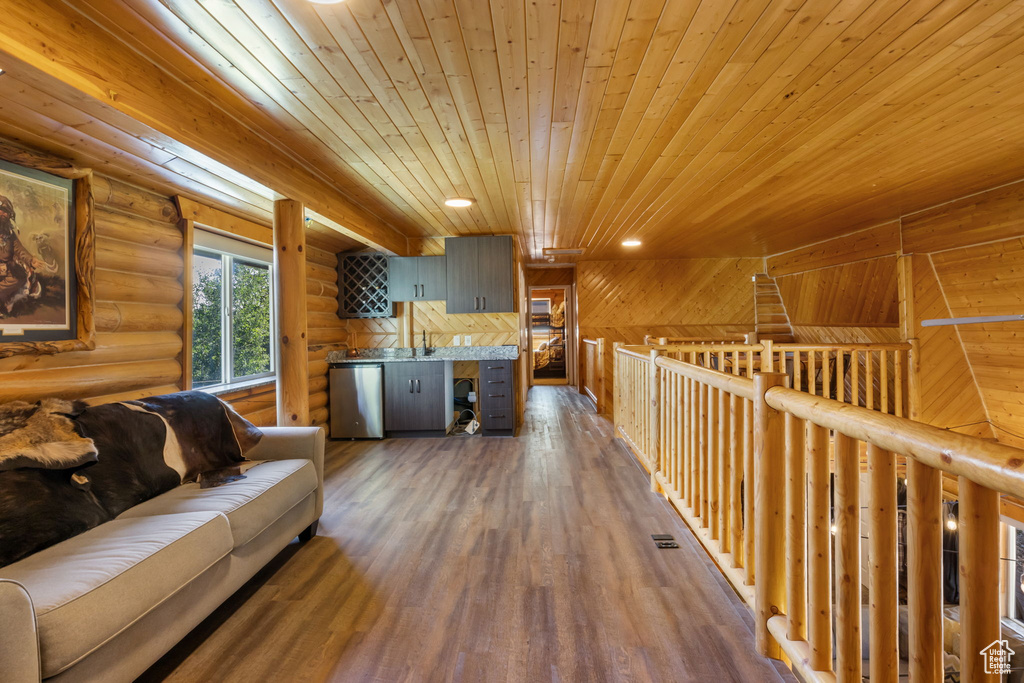 Living room featuring wooden ceiling, log walls, recessed lighting, and wood finished floors
