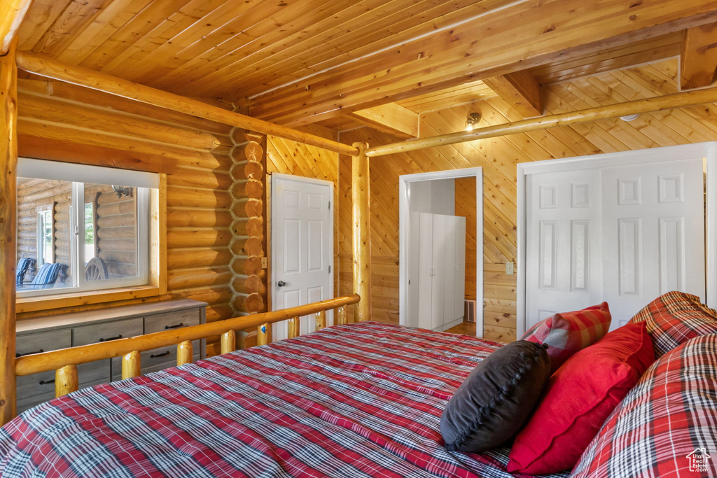 Bedroom with wood ceiling, rustic walls, and beam ceiling