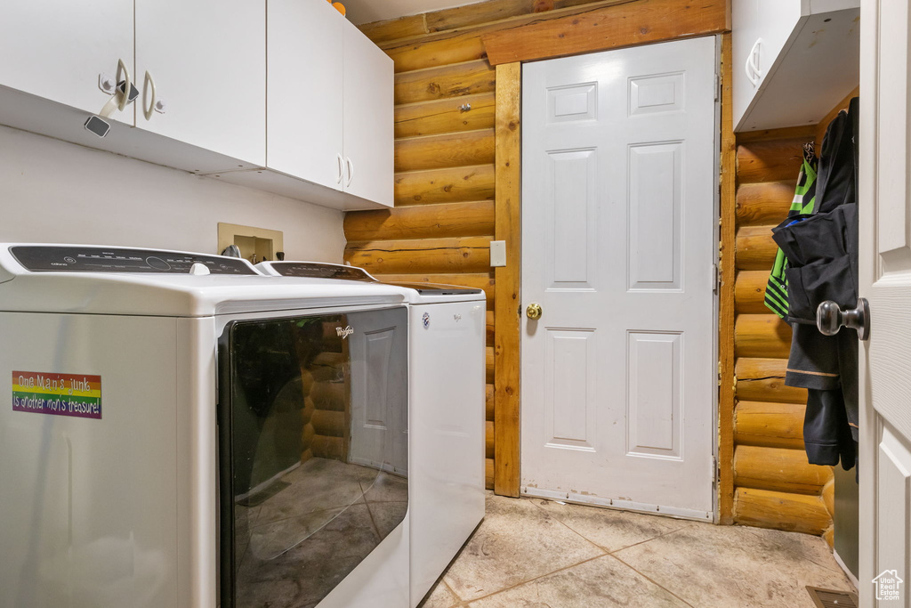 Laundry room featuring log walls, cabinet space, and independent washer and dryer