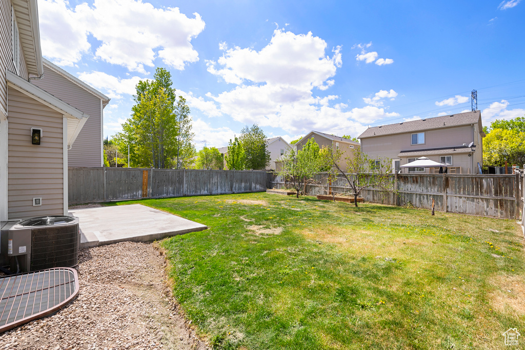 View of yard with central air condition unit, a residential view, a fenced backyard, and a patio area