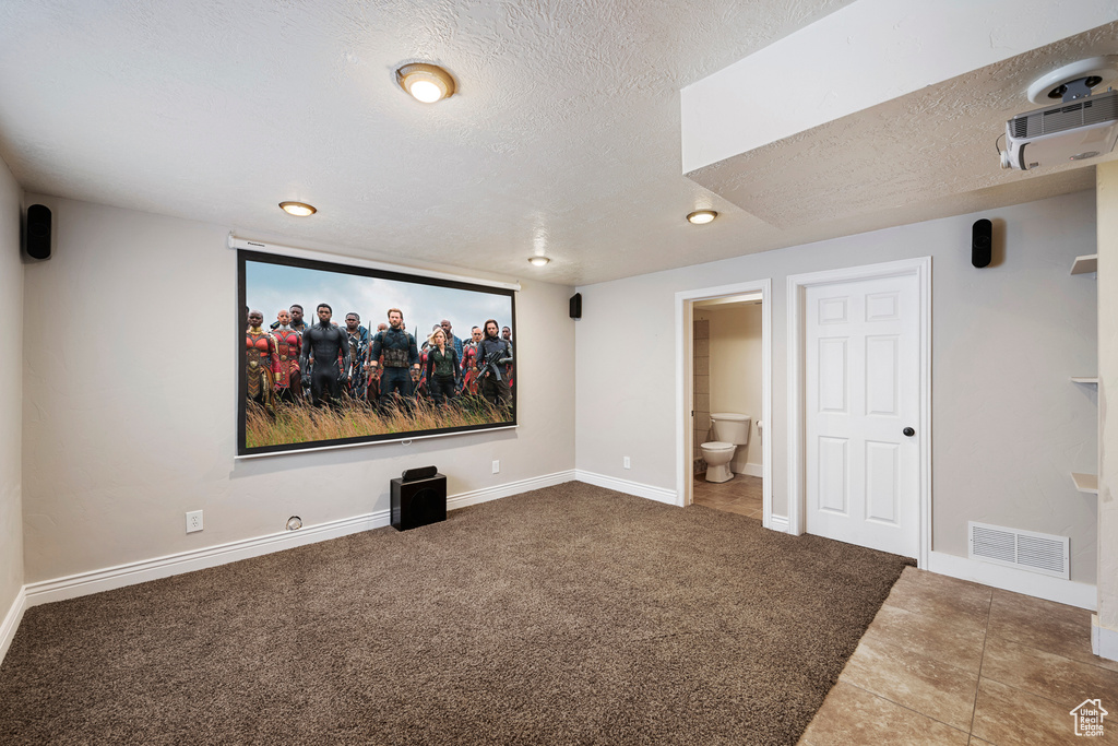 Carpeted cinema with baseboards, tile patterned floors, a textured ceiling, and visible vents
