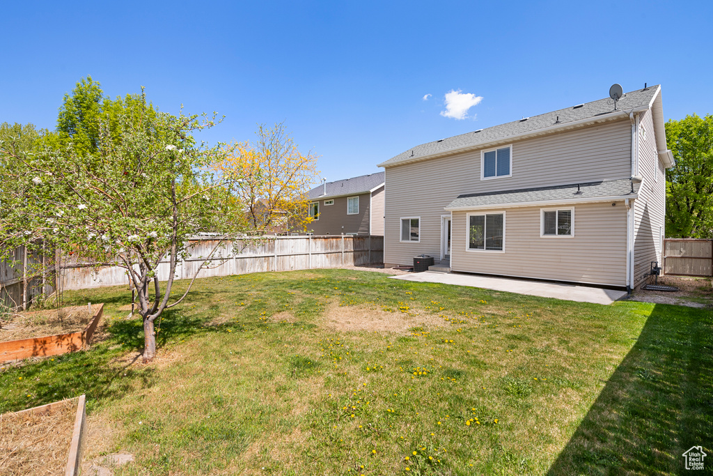 Rear view of house featuring a patio, a fenced backyard, a yard, and a vegetable garden