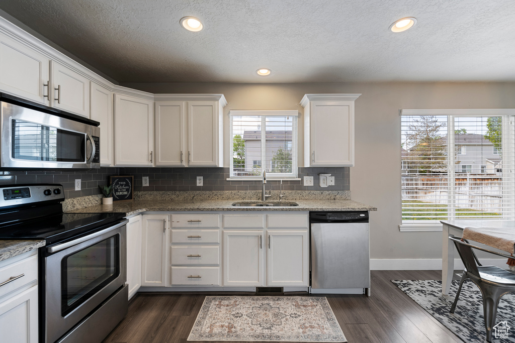 Kitchen featuring dark wood-style flooring, baseboards, appliances with stainless steel finishes, and a sink