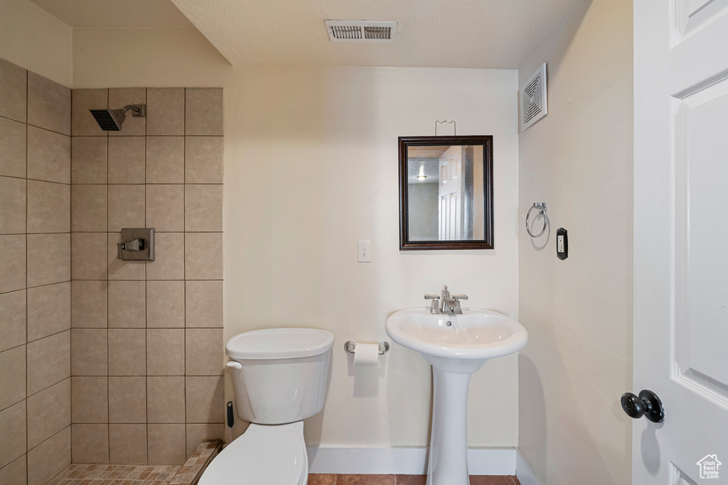 Full bath featuring visible vents, baseboards, toilet, and tiled shower