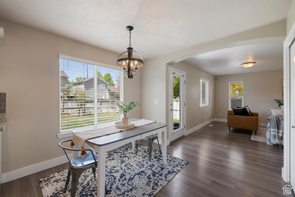 Dining room with arched walkways, baseboards, a chandelier, and a wealth of natural light