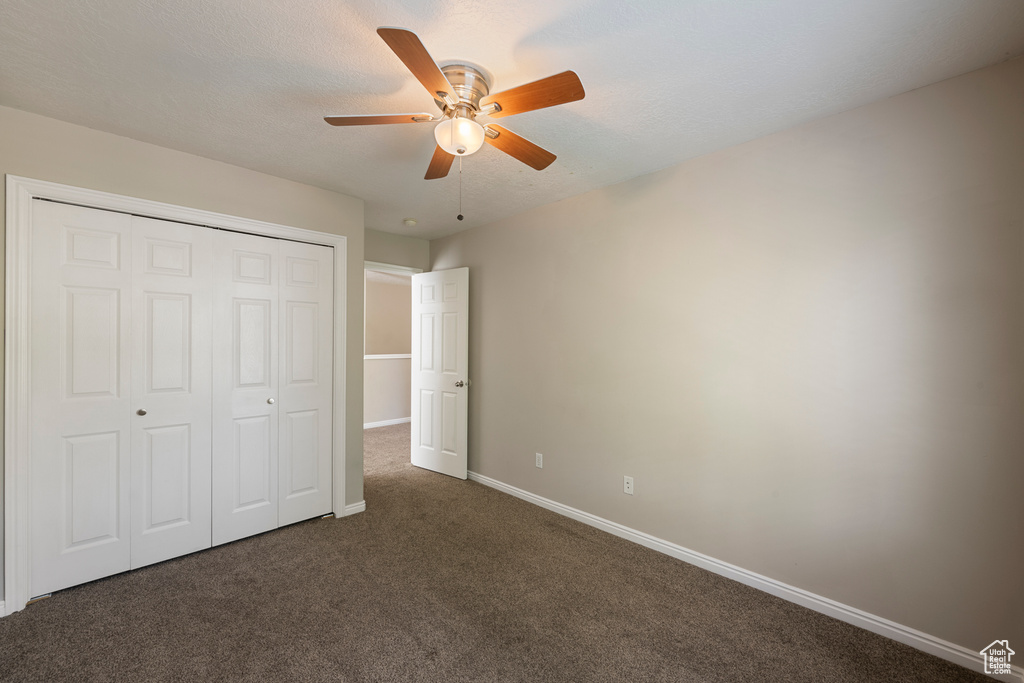 Unfurnished bedroom with carpet floors, baseboards, ceiling fan, and a closet