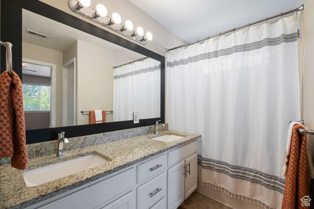 Full bathroom featuring double vanity, visible vents, and a sink