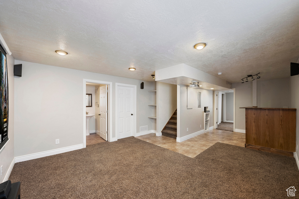 Interior space with stairs, a textured ceiling, baseboards, and carpet flooring